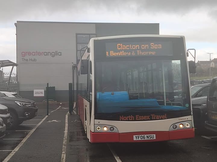 Red and cream North Essex Travel bus with a Clacton on Sea destination display, parked outside a Greater Anglia building