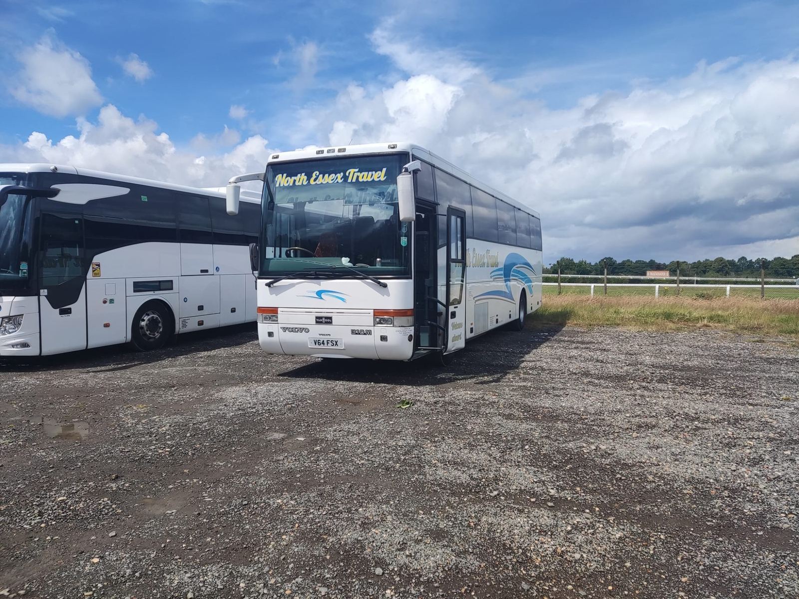 Two North Essex Travel coaches parked on a gravel yard under a wide sky